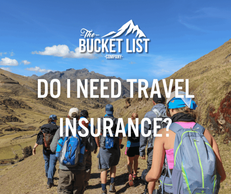 A group of hikers with backpacks walk along a mountain trail under a blue sky; white text reads "The Bucket List Company" and "Do I need travel insurance?