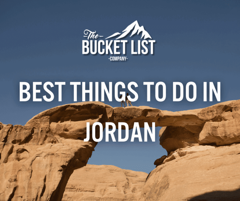 A person stands on top of a natural rock arch under a clear blue sky with the text "The Bucket List Company: Best Things to Do in Jordan" overlaid on the image