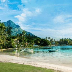 Calm lagoon in Mauritius with small boats anchored near a palm-lined beach and mountain backdrop.