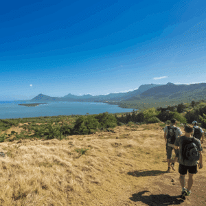 Group hiking along a hillside trail in Mauritius with panoramic views over the lagoon and mountains.