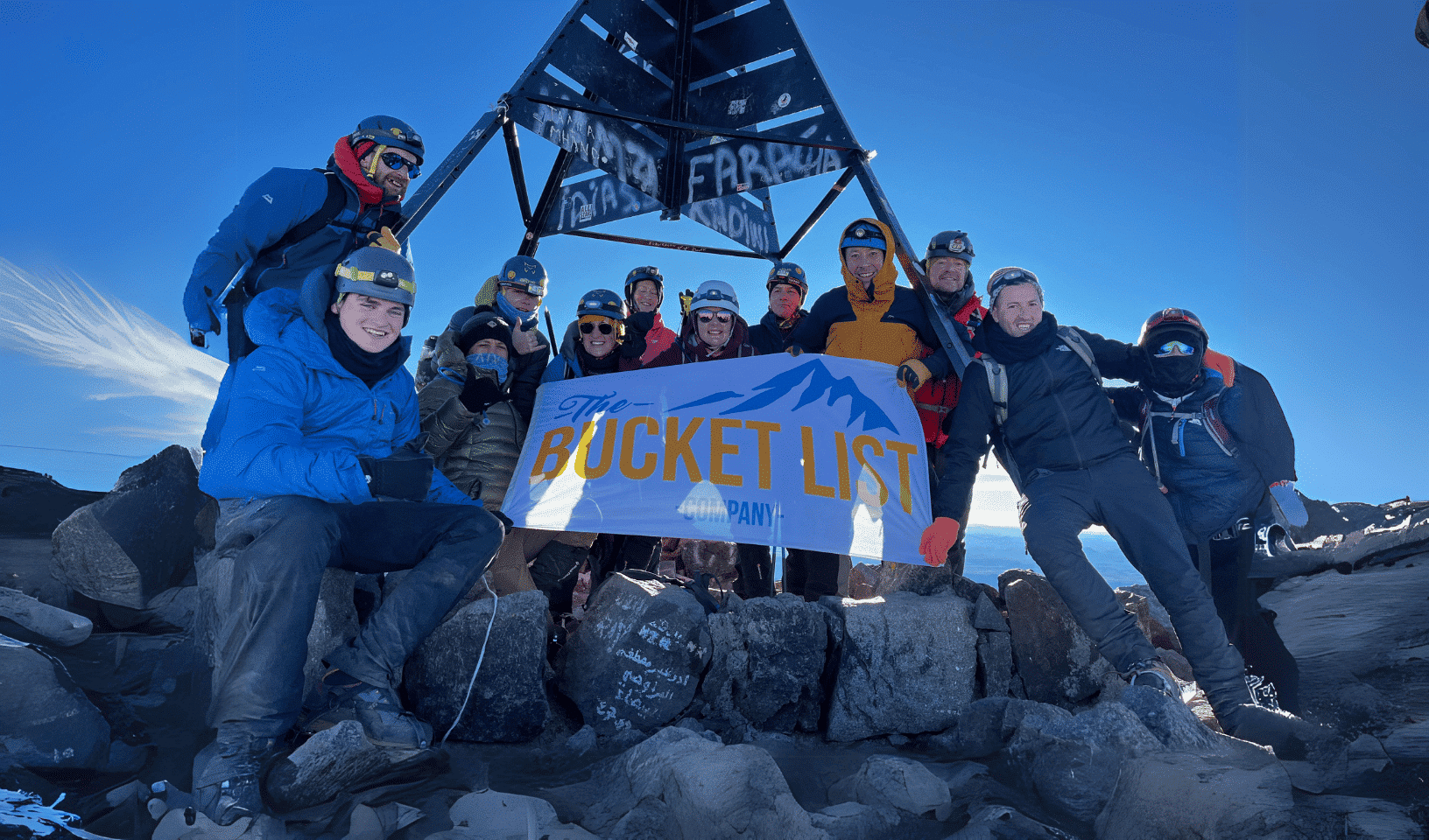 Group of trekkers celebrating at the summit of Mount Toubkal in winter